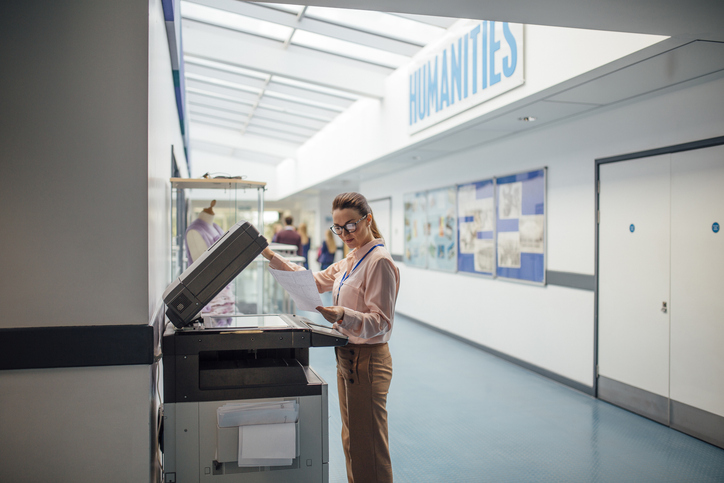 Teacher is printing off work sheets for her next lesson using the printer in the school hall.